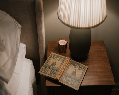 A warm lit desk lamp highlighting an open paper book on a nightstand table layout