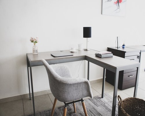 A laptop on a clean wooden table with soft indirect light coming from a side lamp